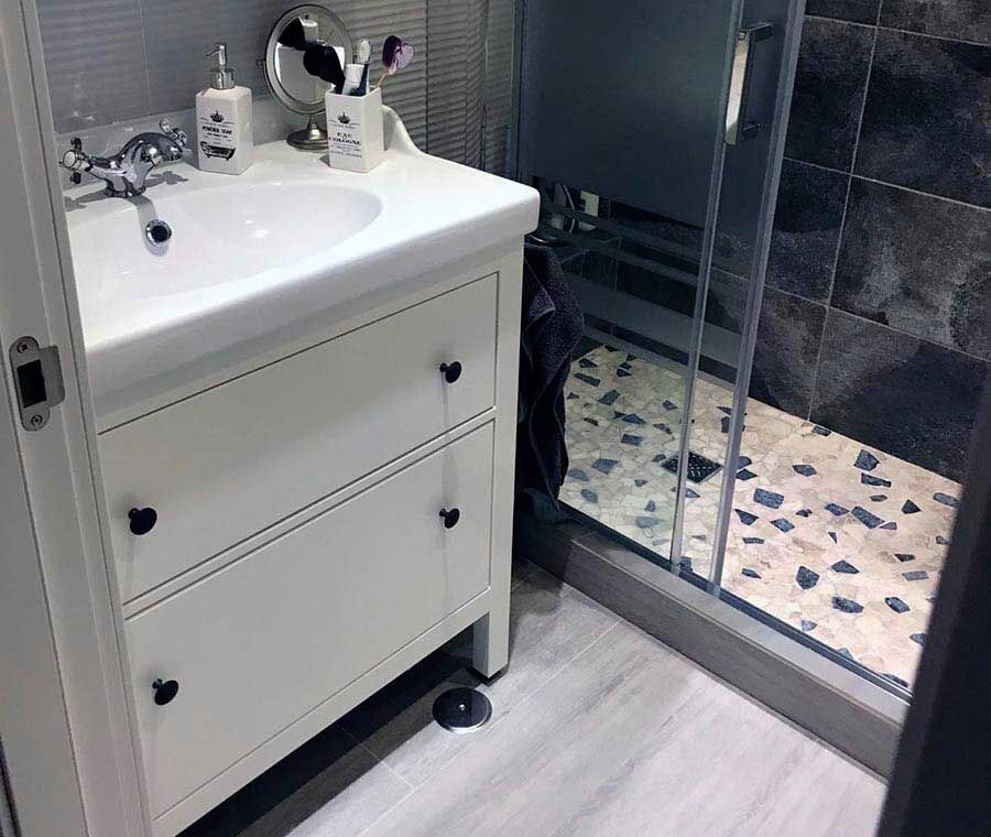 Cuarto de baño reformado con plato de ducha y mueble blanco por Reformas RMB en Madrid