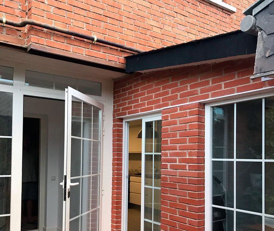 Fachada de ladrillo con carpintería nueva rehabilitada por Reformas RMB